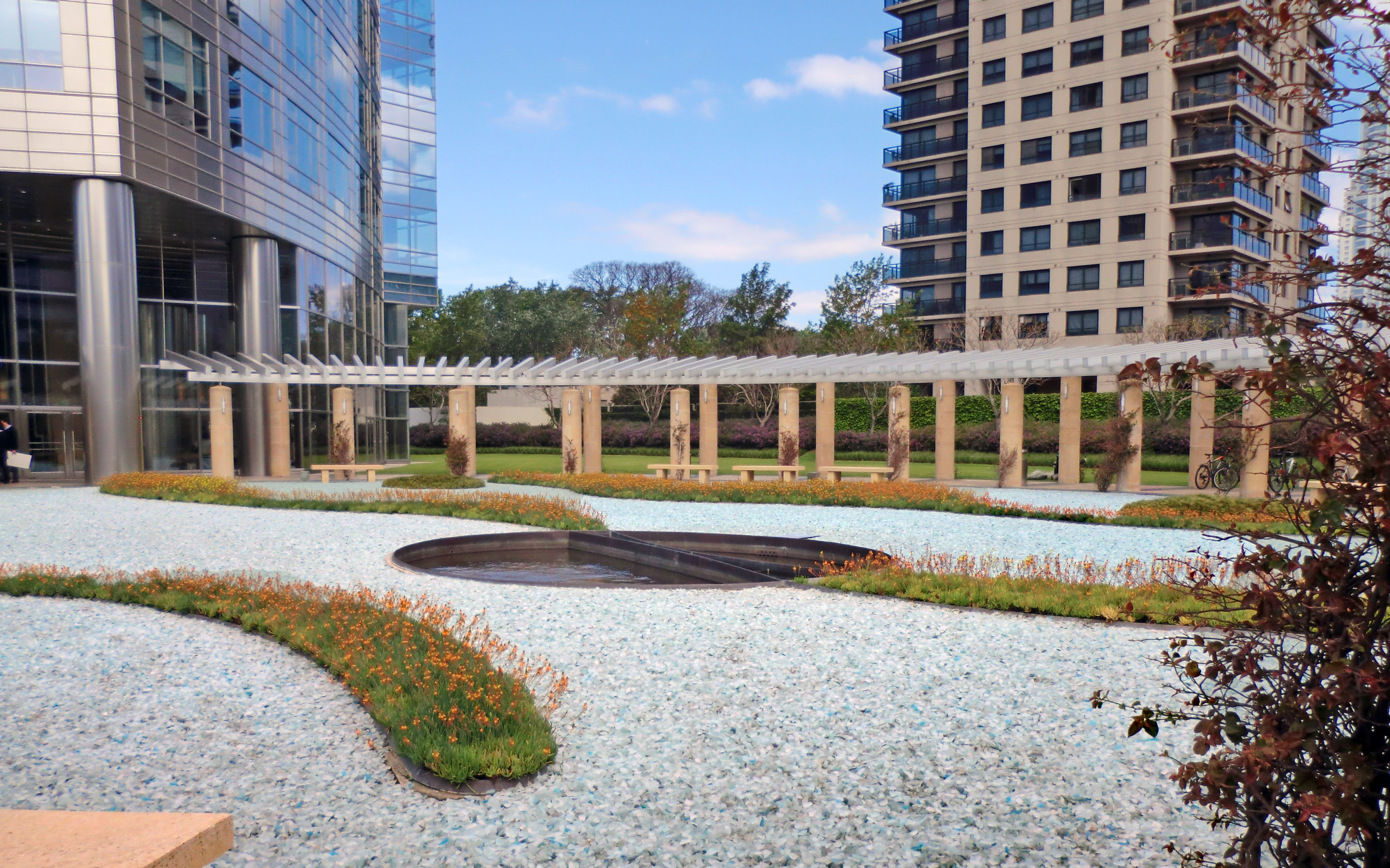 A walkway between pillars divides the garden. Roof garden with pillars, glass gravel paths and planted beds